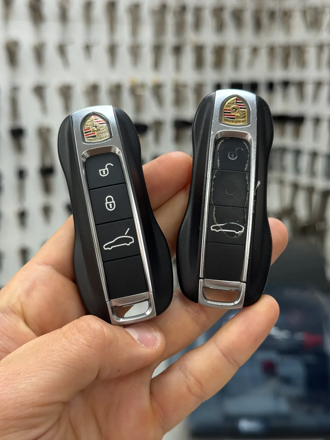 An old and a newly made key in the Keno workshop, a wall of key blanks behind